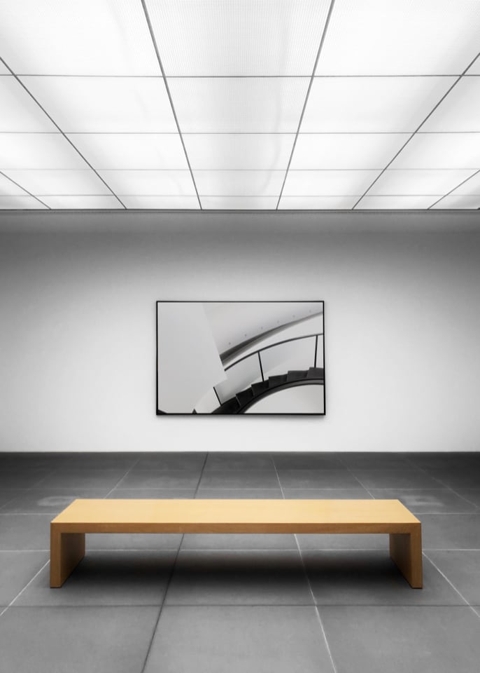 An empty art gallery room with a bench placed in front of a painting, creating a serene and contemplative atmosphere